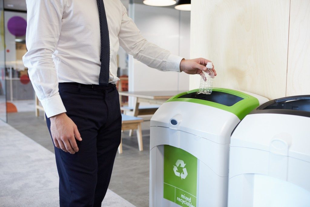 business man throwing plastic bottle in recycle bin