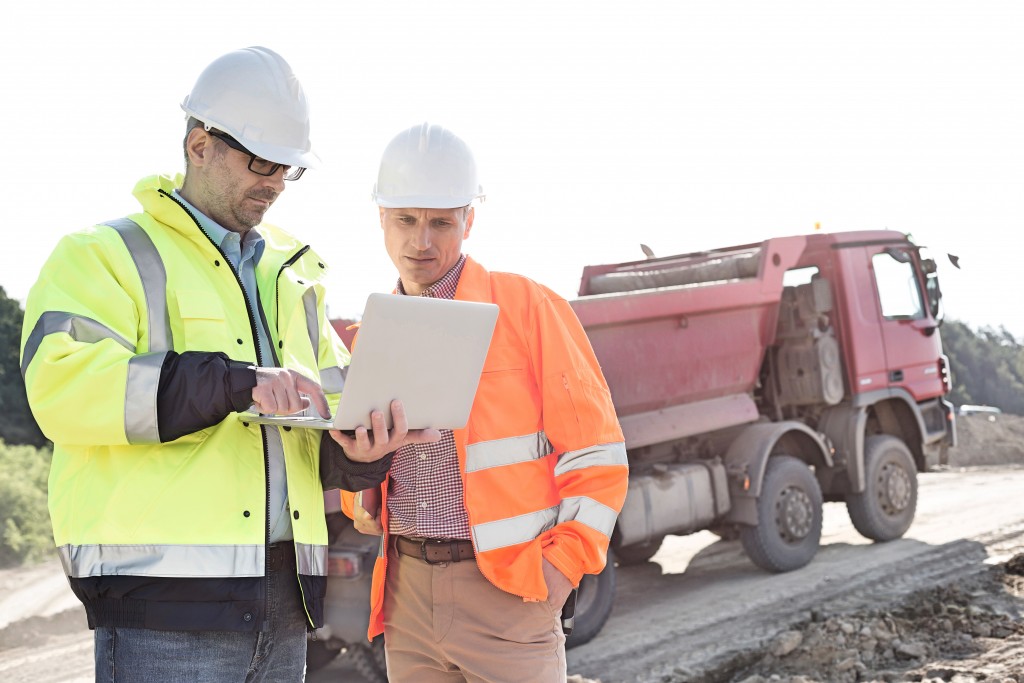 contractors holding laptop at a construction site