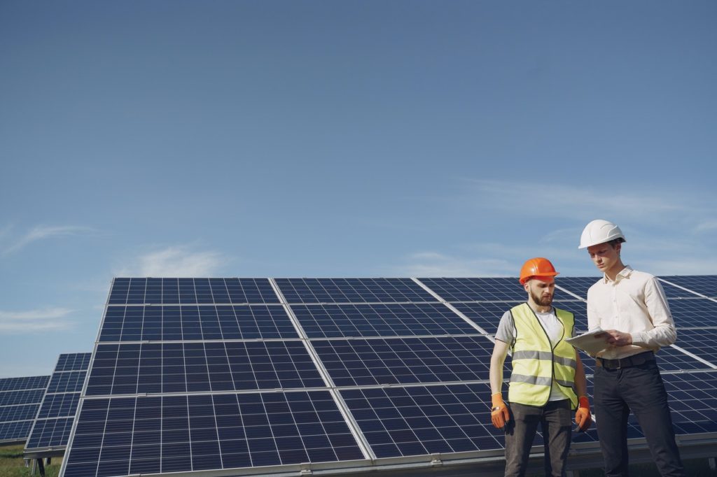 two people standing in front of some solar panels