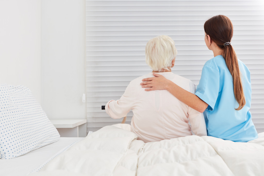 a senior woman supported by a care provider in bed